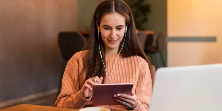 Mulher estudando online com tablet e computador para participar de curso de formação cultural.