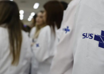 Profissionais de saúde vestindo jalecos do SUS durante atendimento hospitalar.