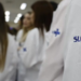 Profissionais de saúde vestindo jalecos do SUS durante atendimento hospitalar.
