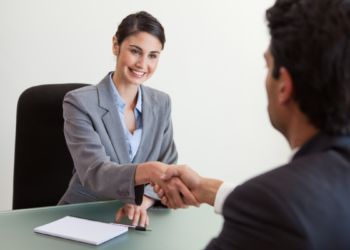Recrutadora cumprimenta candidato em entrevista de emprego.