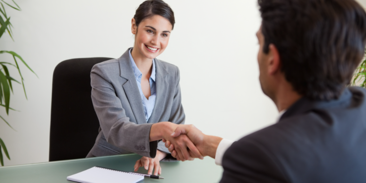 Recrutadora cumprimenta candidato em entrevista de emprego.