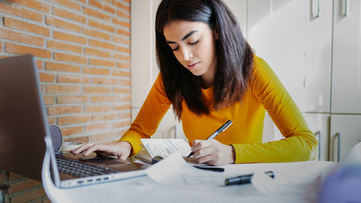 Jovem mulher estuda concentrada diante de notebook em ambiente moderno.