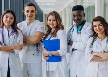 Residentes da saúde reunidos em corredor de hospital.