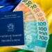 Carteira de trabalho e notas de real sobre bandeira do Brasil.