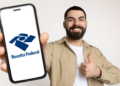 Jovem exibe aplicativo da Receita Federal em celular com expressão positiva.