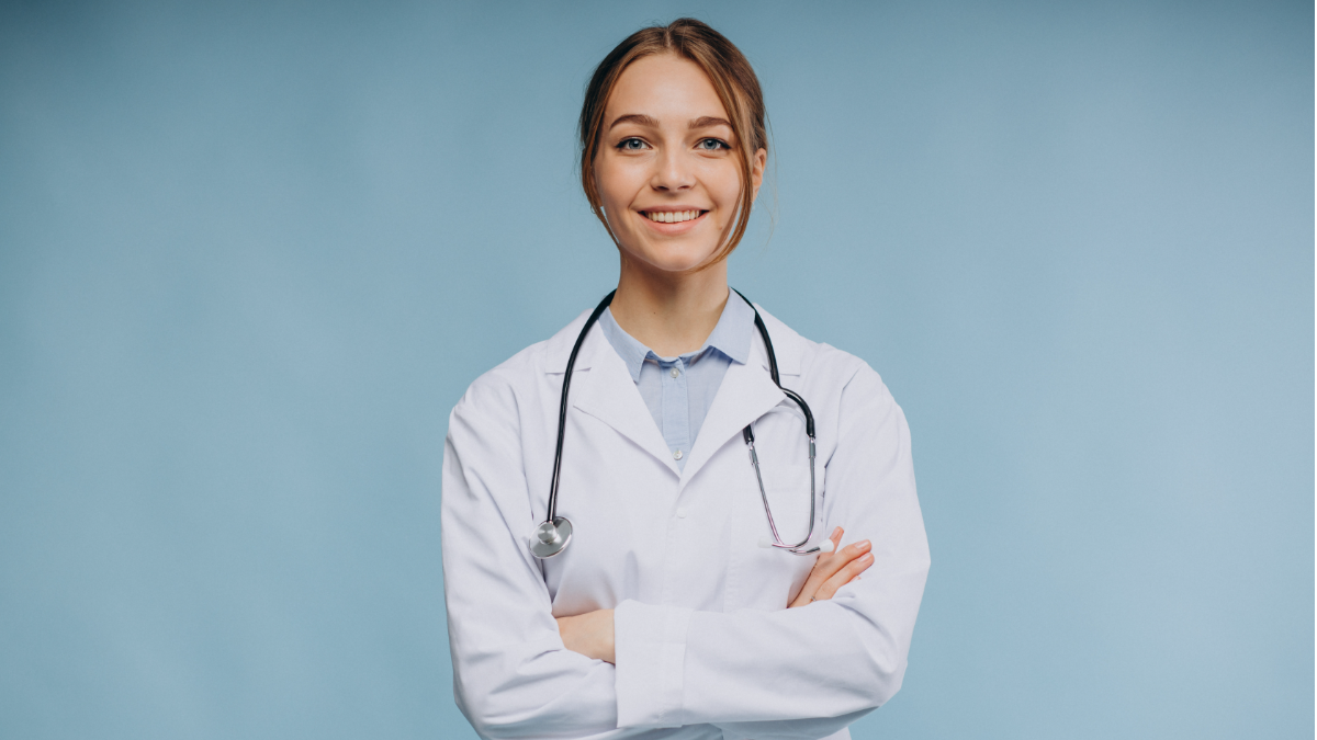 Médica jovem sorridente com jaleco branco e estetoscópio.