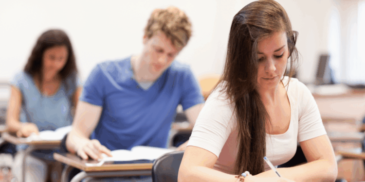 Estudantes focados realizando prova em sala de aula.