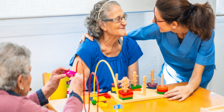 Terapeuta ocupacional estimulando idosas com jogos cognitivos em ambiente acolhedor.