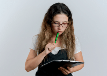 Jovem analisa anotações enquanto pensa durante estudo.