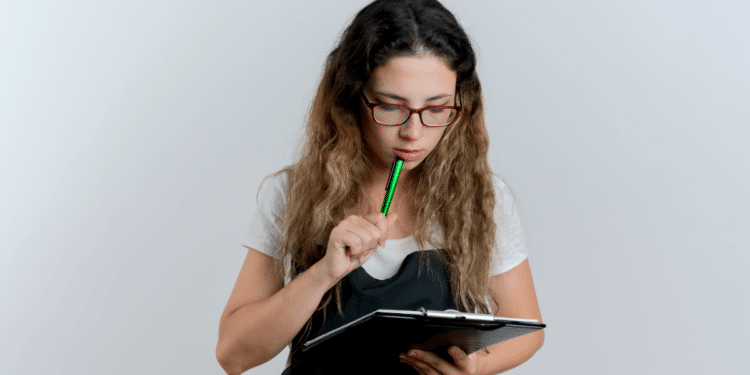 Jovem analisa anotações enquanto pensa durante estudo.