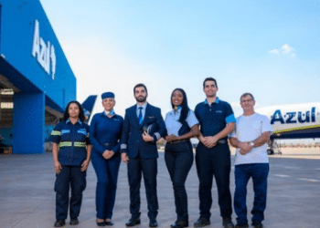 Equipe de profissionais da Azul Linhas Aéreas reunida em frente a avião e hangar.