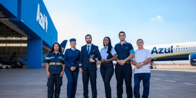 Equipe de profissionais da Azul Linhas Aéreas reunida em frente a avião e hangar.