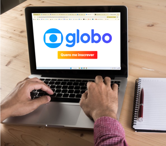 Tela de inscrição Globo acessada em notebook com bloco de notas ao lado.