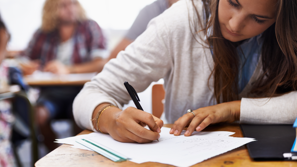 Estudante concentrada realizando prova em sala de aula.