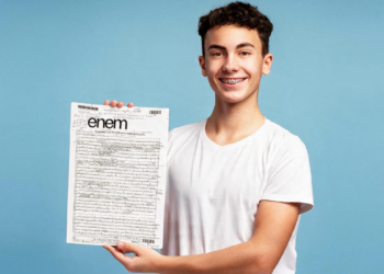 Estudante com aparelho sorrindo ao mostrar prova do Enem.