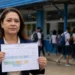 Diretora segura calendário escolar de 2027 em frente a escola pública, representando orientação do CNE para ajustes durante a Copa Feminina.