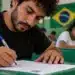 Candidato estrangeiro realiza prova escrita de português em sala de aula, representando a aplicação do exame de proficiência em língua portuguesa para estrangeiros em 2026.