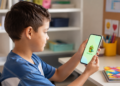 Criança utiliza o aplicativo Papuguinho no celular para apoio à comunicação.