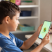 Criança utiliza o aplicativo Papuguinho no celular para apoio à comunicação.