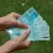 Mãos segurando cédulas de real representando o auxílio financeiro da Bolsa Permanência do ProUni.