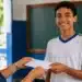 Aluno do 9º ano recebe documento em escola, representando o acesso a bolsas integrais em escolas privadas.