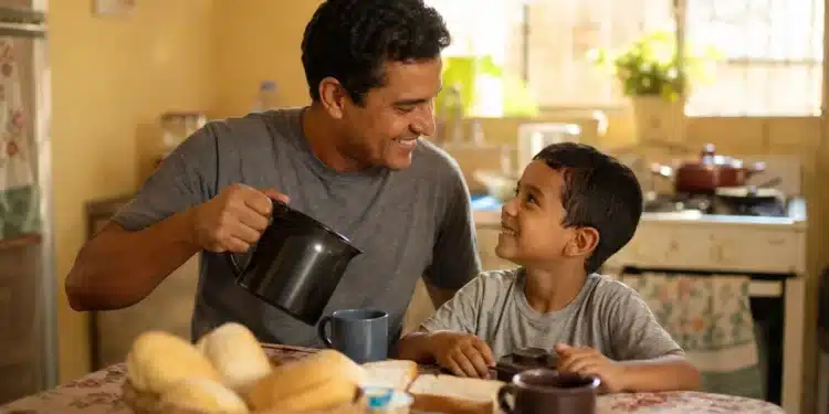Pai e filho compartilham um café da manhã simples, representando uma comemoração econômica do Dia dos Pais.