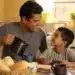 Pai e filho compartilham um café da manhã simples, representando uma comemoração econômica do Dia dos Pais.