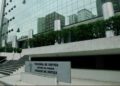 Fachada envidraçada do Palácio da Justiça, sede do Tribunal de Justiça do Paraná, com a placa de identificação em primeiro plano.