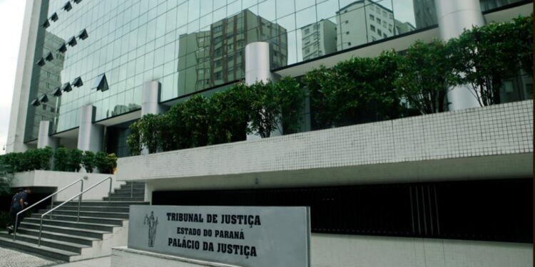 Fachada envidraçada do Palácio da Justiça, sede do Tribunal de Justiça do Paraná, com a placa de identificação em primeiro plano.