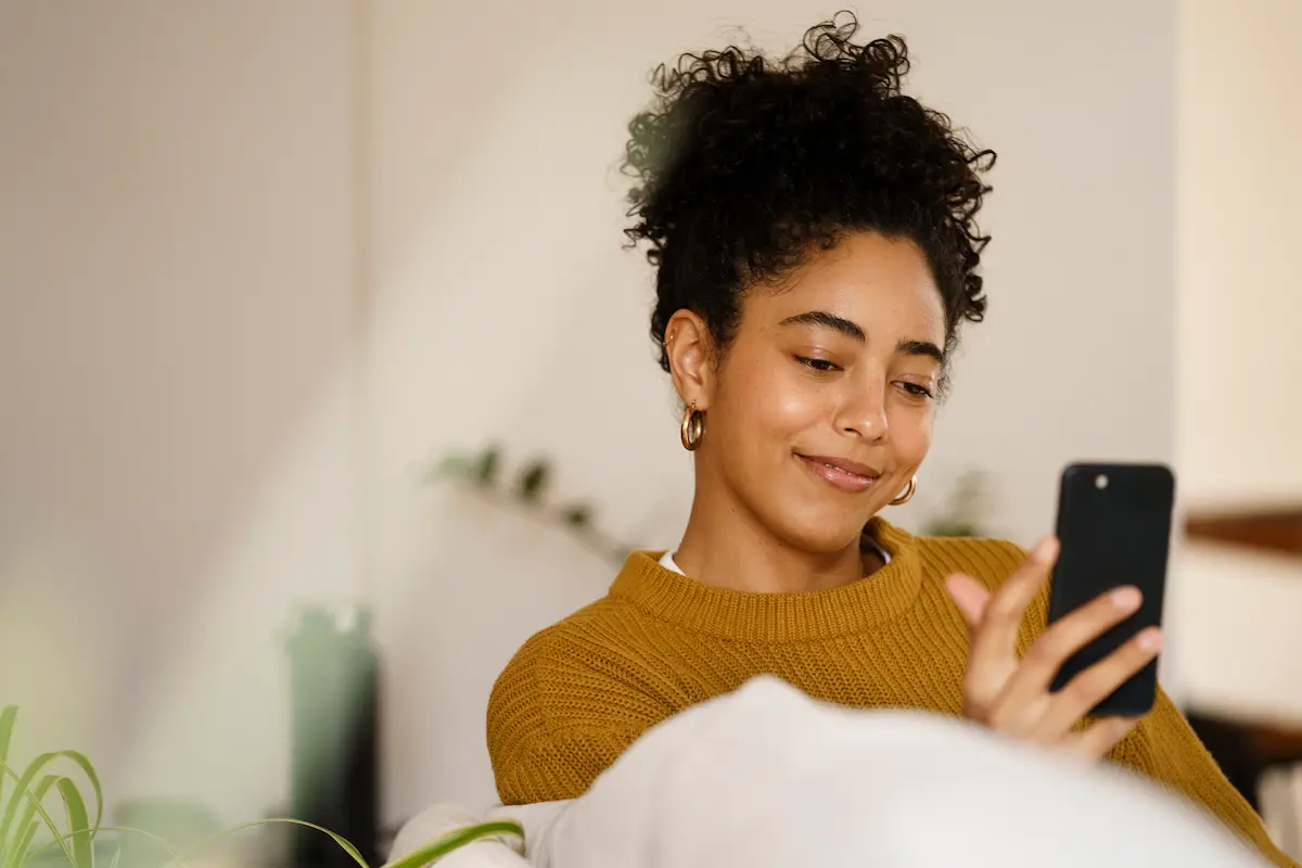 Mulher acessa informações sobre cursos gratuitos do programa Mulheres Mil pelo celular.