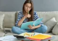 Estudante revisa conteúdos em casa com caderno e notebook durante rotina de estudos.