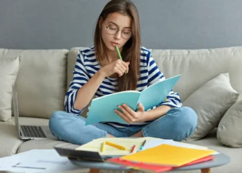Estudante revisa conteúdos em casa com caderno e notebook durante rotina de estudos.