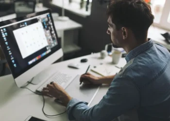 Profissional criativo trabalha em computador com recursos de design e produção visual.