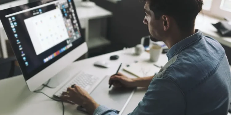 Profissional criativo trabalha em computador com recursos de design e produção visual.