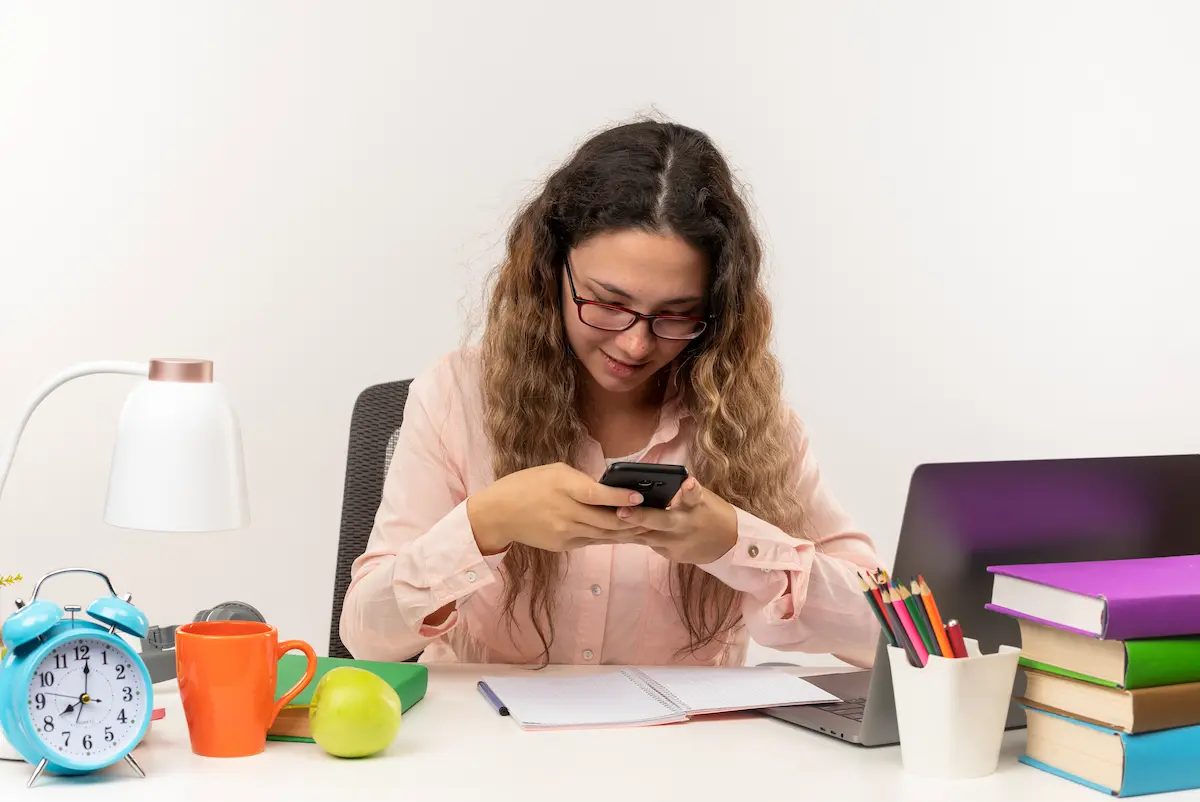 Estudante consulta informações pelo celular durante estudos representando a renegociação de contratos pelo Desenrola Fies.