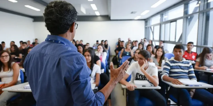 Professor ministra aula para estudantes em sala, em referência ao Dia dos Profissionais da Educação.