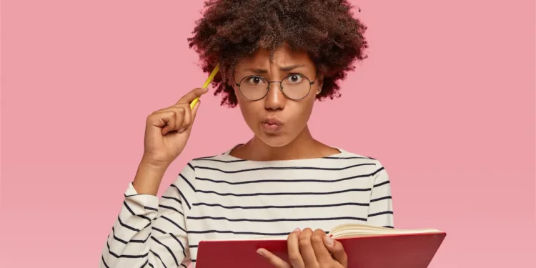 Mulher estudando português com livro e caneta enquanto reflete sobre o uso correto da expressão “Eu vi ele”.