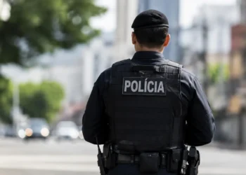 Policial fardado visto de costas durante patrulhamento em uma rua, representando os concursos policiais previstos para 2026.