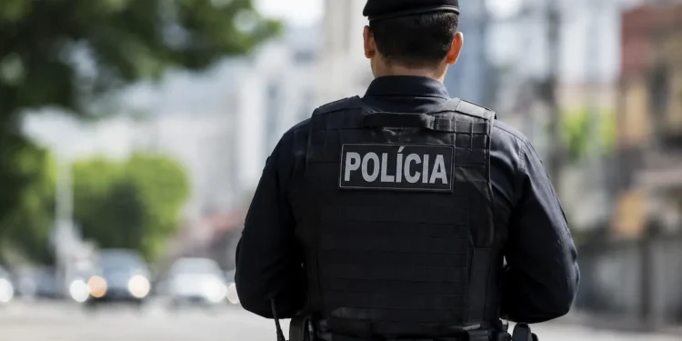 Policial fardado visto de costas durante patrulhamento em uma rua, representando os concursos policiais previstos para 2026.