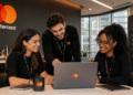Profissionais da Mastercard trabalham em equipe durante reunião em escritório em São Paulo.