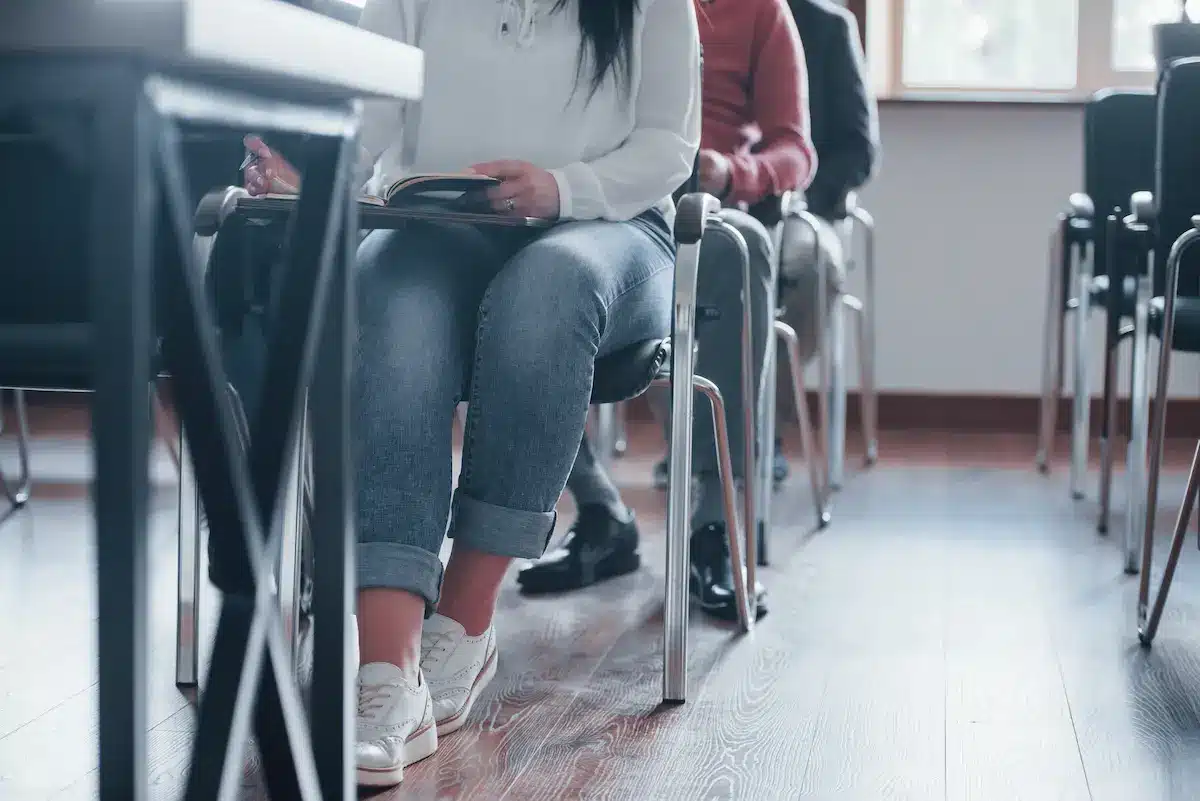 Sala de aula com participantes durante atividade educacional, imagem ilustrativa sobre provas e exames.