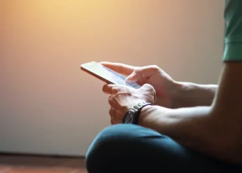 Pessoa acessa informações pelo celular, representando consulta ao cartão de confirmação do Encceja 2026.