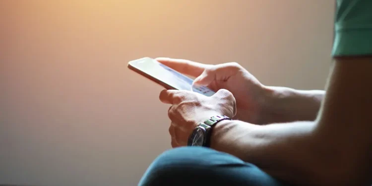 Pessoa acessa informações pelo celular, representando consulta ao cartão de confirmação do Encceja 2026.