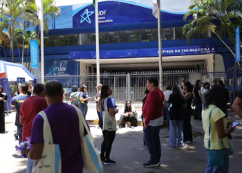 Participantes reunidos na calçada em frente ao portão de um local de prova, com fila se formando na entrada, em referência aos horários definidos pelo Inep para o Encceja 2026