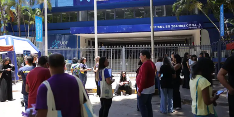 Participantes reunidos na calçada em frente ao portão de um local de prova, com fila se formando na entrada, em referência aos horários definidos pelo Inep para o Encceja 2026