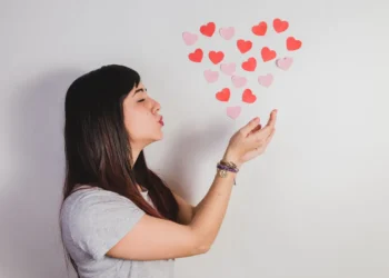Mulher soprando corações para representar a expressão “eu te amo” na língua portuguesa.