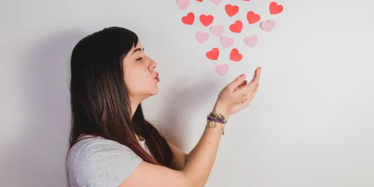 Mulher soprando corações para representar a expressão “eu te amo” na língua portuguesa.
