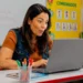 Professora da educação básica utilizando notebook em sala de aula, representando uma formação sobre inteligência artificial e educação digital.