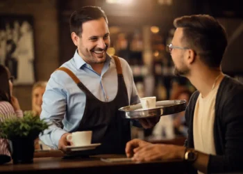Garçom realizando atendimento em restaurante durante serviço de mesa.