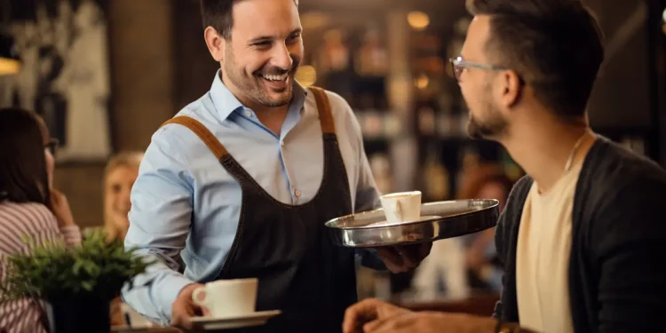 Garçom realizando atendimento em restaurante durante serviço de mesa.